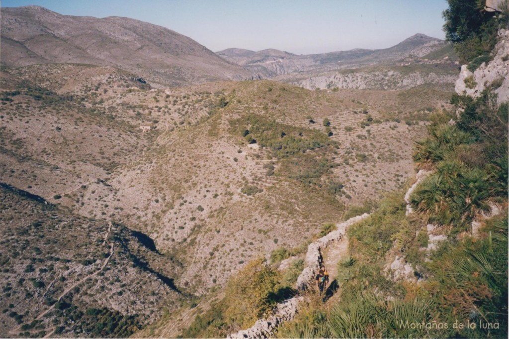 Se aprecia la linea blanca del camino en la montaña como baja de Les Juvees del Poble de Dalt por el Barranc del Tuerto (centro izquierda) hasta el Barranc dels Racons (abajo izquierda) y aparece subiendo hacia la Font dels Olbitsa (abajo derecha), arriba a la izquierda la Sierra de La Carrasca
